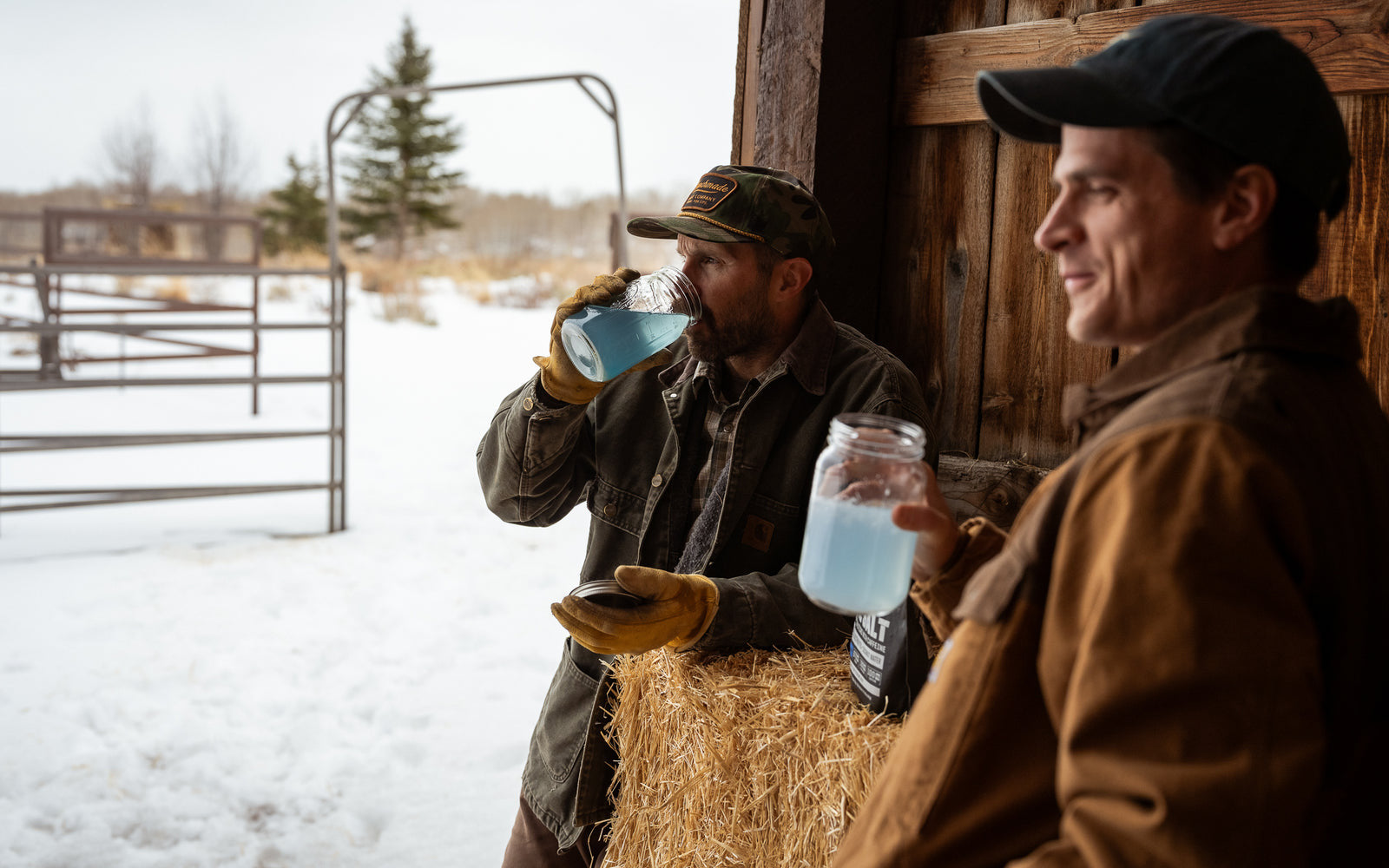 Two people outdoors on a winter morning, one of them drinking a mixed Fire Salt hydration stick from a glass jar.